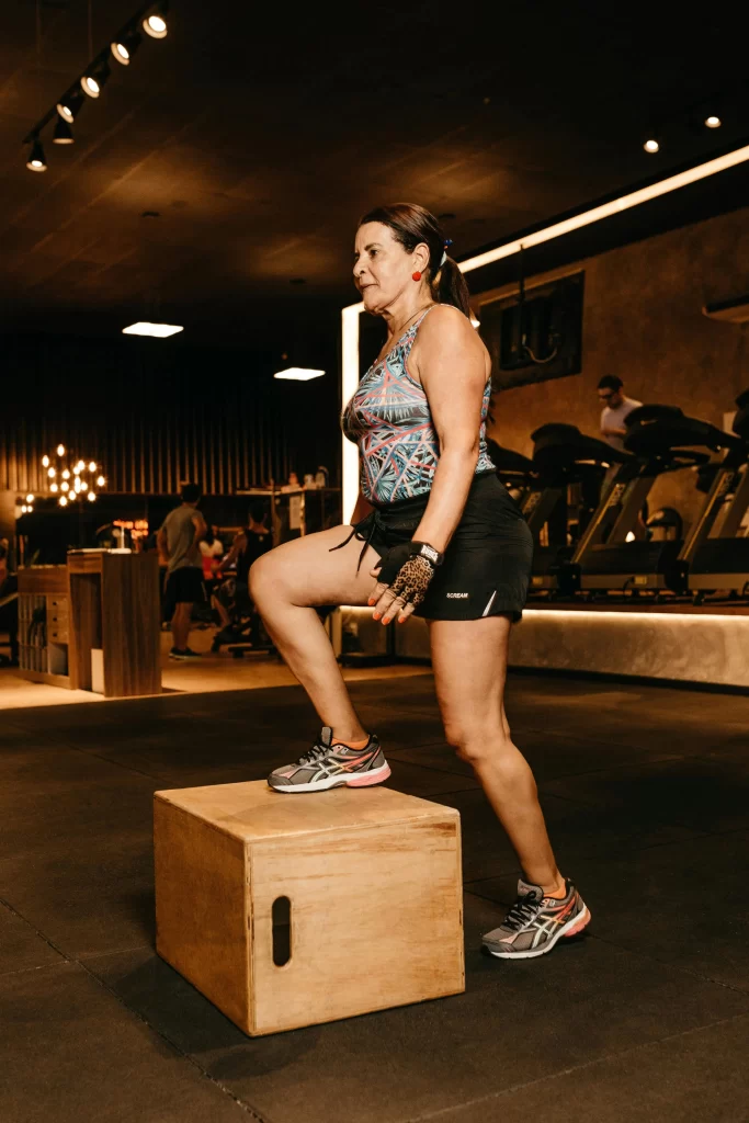 Energetic woman in her prime performing box step-ups in a modern gym.